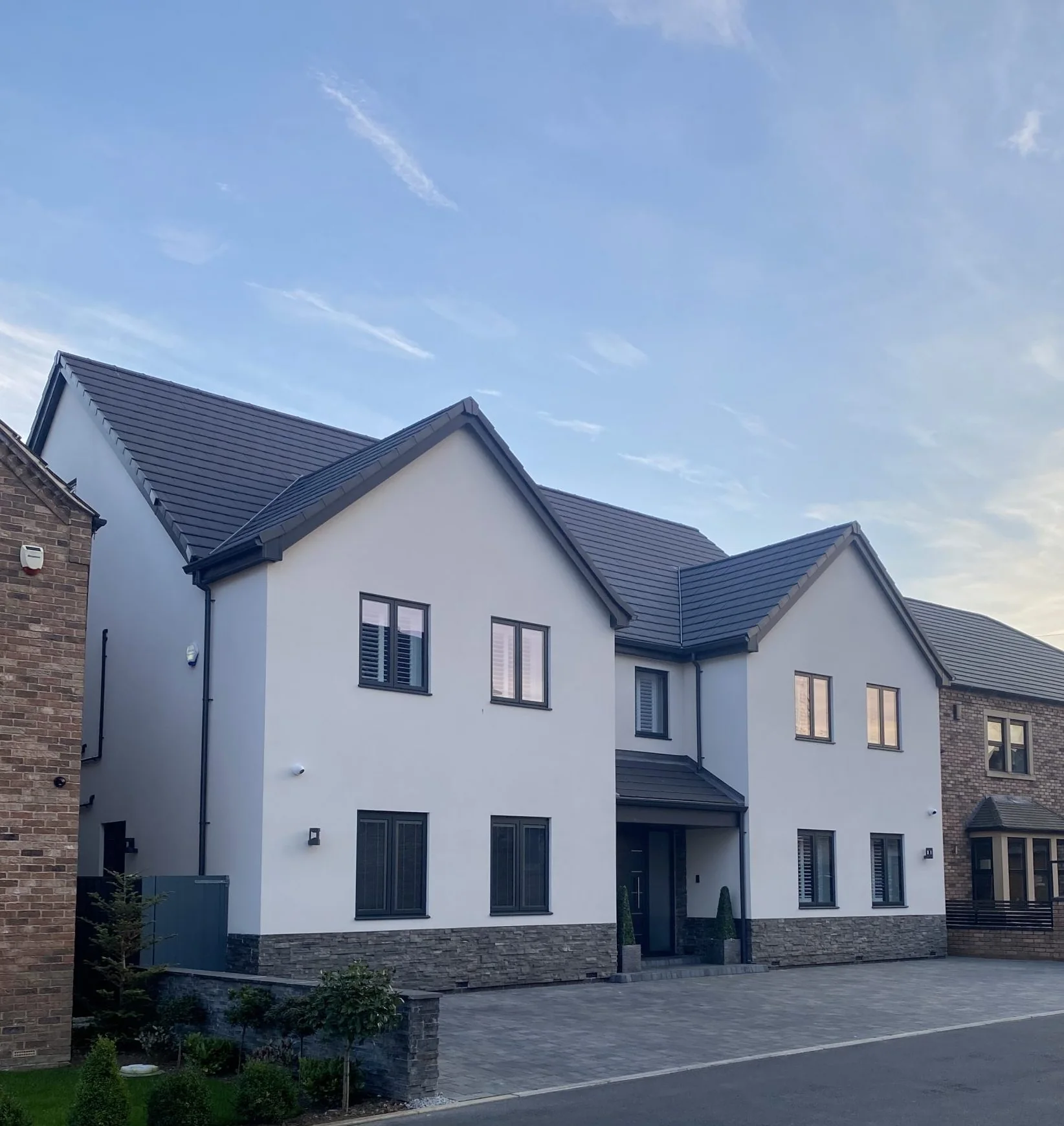 White rendered gabled home with stone detailing at Earlswood Court